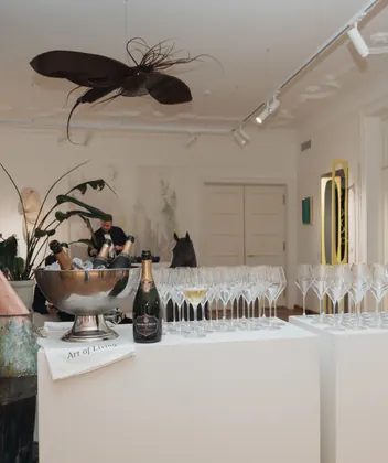 The KOOS gallery room set for an event, coupes on plinths beneath a suspended sculpture